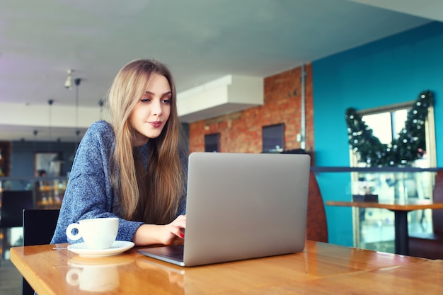 Donna che lavora al computer portatile in un caffè