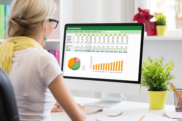 Donna che lavora con dati e grafici nel foglio di calcolo sul computer desktop