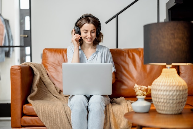 Donna che lavora con laptop e cuffie da casa