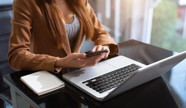 Donna che lavora con smartphone e computer portatile in ufficio