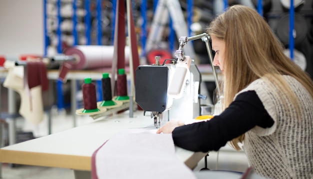 donna che lavora concentrata con una macchina da cucire industriale