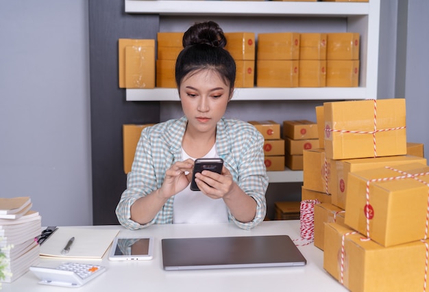 Donna che lavora e che controlla l&#39;ordine del prodotto con l&#39;ufficio dello smartphone a casa