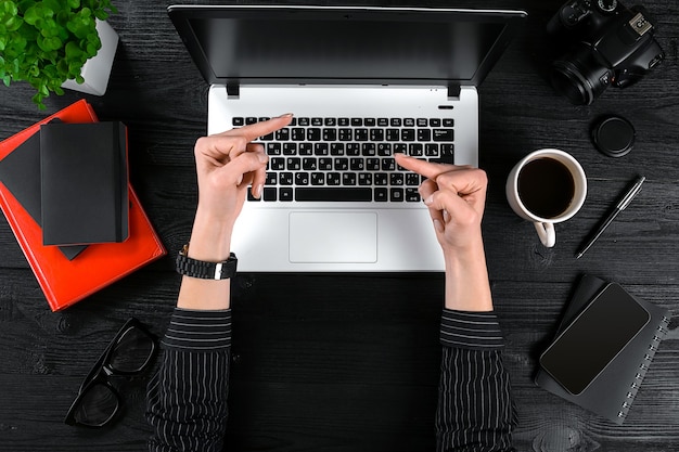 Donna che lavora in ufficio vista dall'alto del tavolo delle mani umane tastiera del laptop una tazza di caffè smartphone...