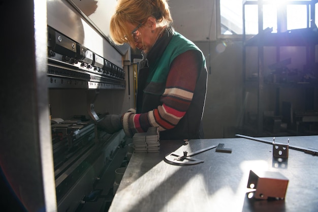 donna che lavora in una fabbrica moderna e prepara materiale per una macchina CNC. . Foto di alta qualità