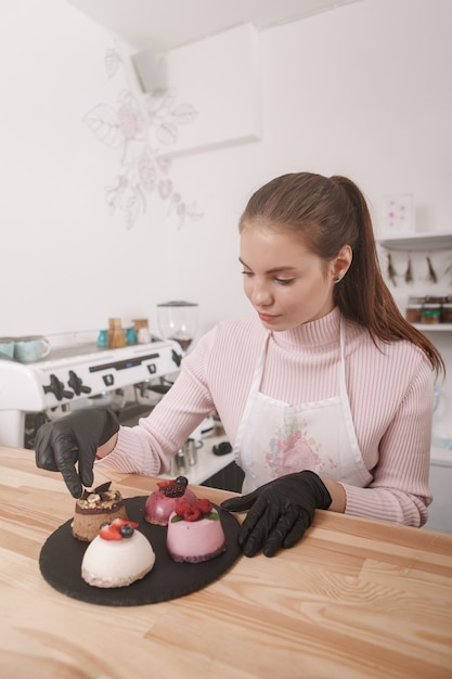 Donna che lavora presso la sua caffetteria decorando deliziosi dessert