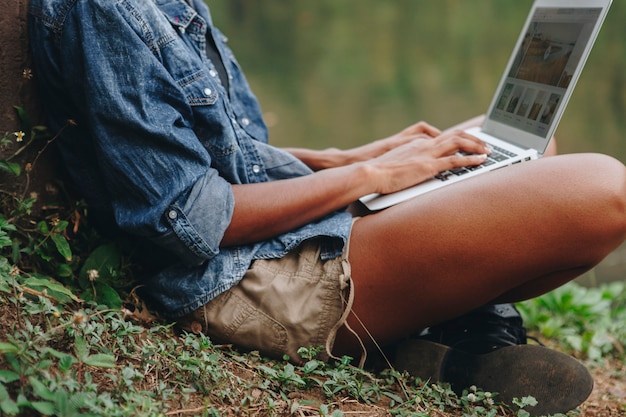 Donna che lavora su un computer portatile nella natura