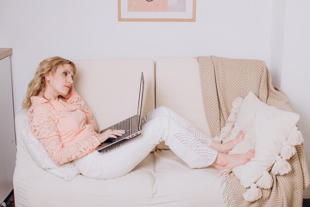 Donna che lavora su un laptop mentre è sdraiata sul divano