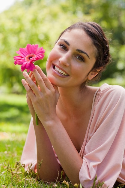 Donna che le arruffa il mento sulle sue mani mentre tiene un fiore