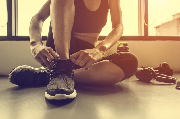 donna che lega i lacci delle scarpe in palestra.