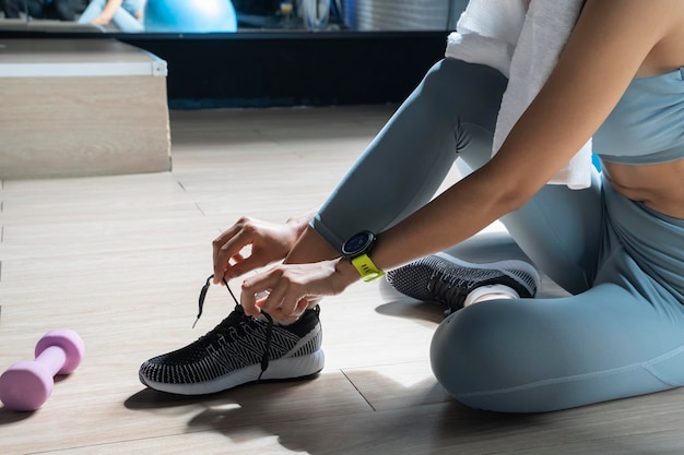 Donna che lega i lacci delle scarpe in palestra