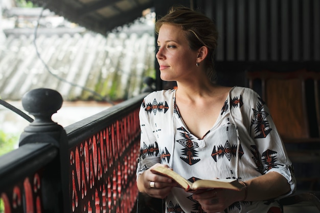 Donna che legge il libro sul balcone