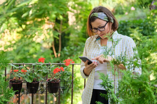 Donna che legge sms di testo, contenuti online su smartphone, donna a casa sul balcone verde aperto, copia spazio