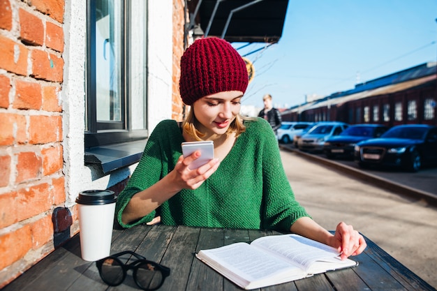 Donna che legge un libro al terrazzo del caffè