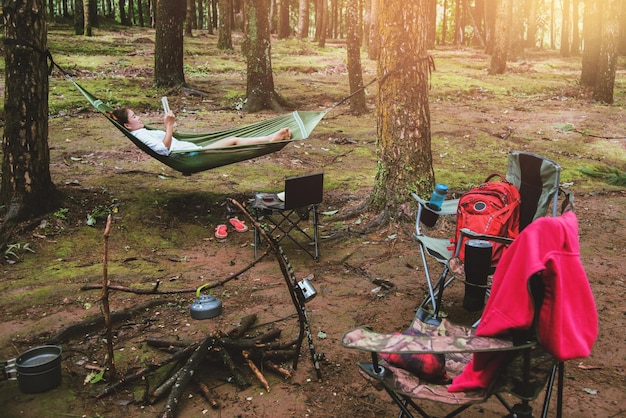 Donna che legge un libro mentre giace nella foresta durante il campeggio