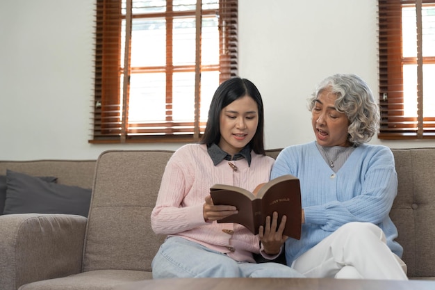 Donna che legge un libro mentre si siede con la nonna felice a casa