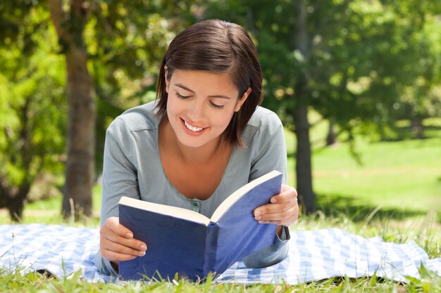 Donna che legge un libro nel parco