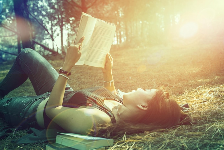 Foto donna che legge un libro sdraiata sull'erba