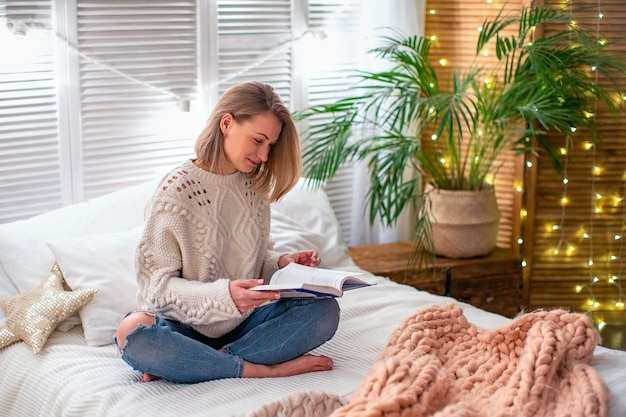 Donna che legge un libro sul letto. una ragazza incontra il Natale