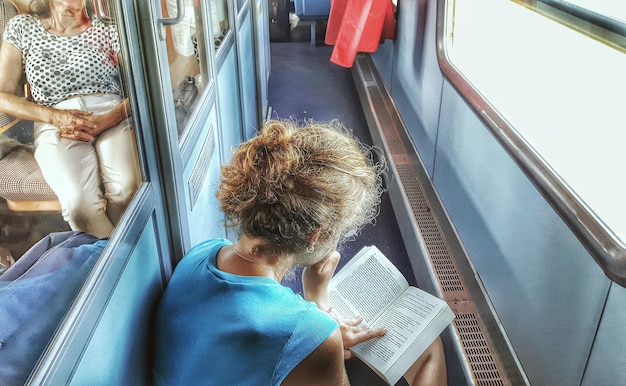 Donna che legge un romanzo nel corridoio del treno