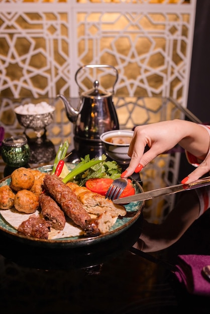 Donna che mangia barbecue in un caffè mani femminili primo piano che tiene una forchetta con un pezzo di barbecue