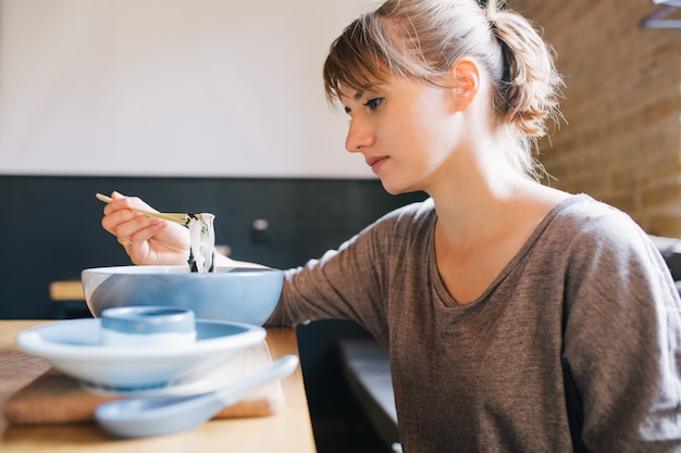 Donna che mangia cibo asiatico