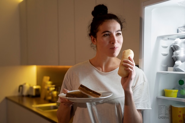 Donna che mangia cibo dal frigo