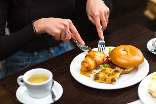 Donna che mangia gustosi cornetti e brioche da forno