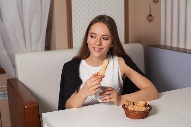 Donna che mangia i biscotti e che beve tè caldo nella caffetteria