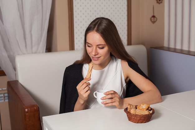 Donna che mangia i biscotti e che beve tè caldo nella caffetteria