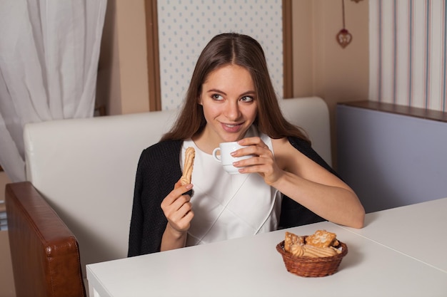 Donna che mangia i biscotti e che beve tè caldo nella caffetteria