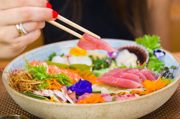 Donna che mangia il primo piano delizioso del sashimi sulle bacchette