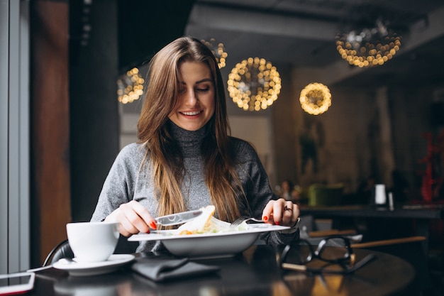 Donna che mangia insalata in un caffè