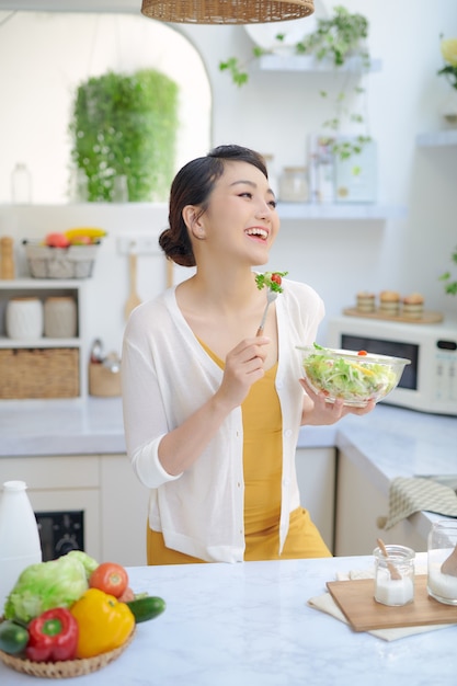 Donna che mangia insalata sana nella cucina moderna