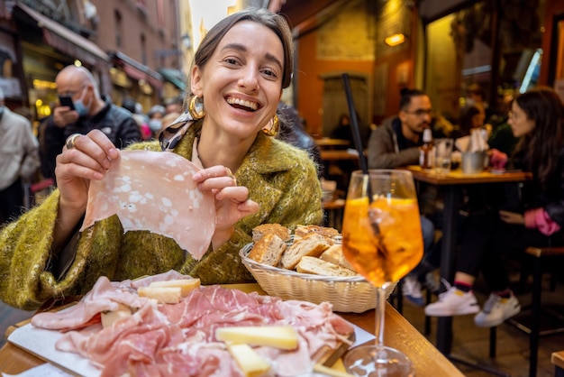 Donna che mangia piatto di carne al bar all'aperto in italia