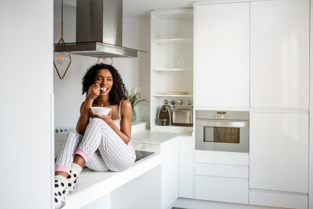 Donna che mangia prima colazione con il telefono cellulare