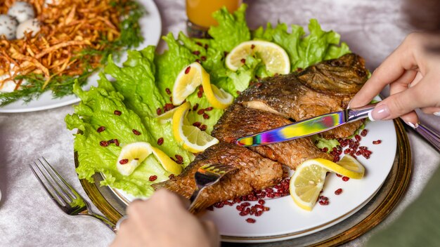 Donna che mangia un pesce intero alla griglia con un limone