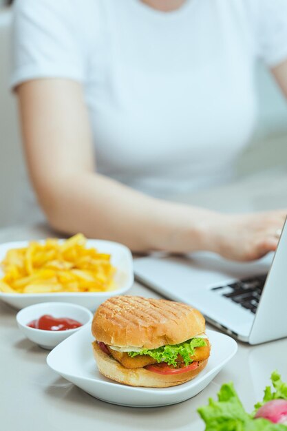 Donna che mangia un pranzo malsano mentre studia corso online in cucina Libero professionista di lavoro a distanza