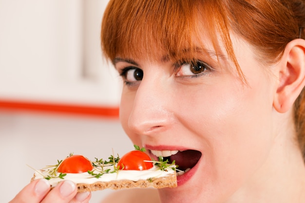 Donna che mangia un toast sano con pomodoro e formaggio