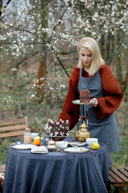 Donna che mangia una torta al cioccolato in un giardino