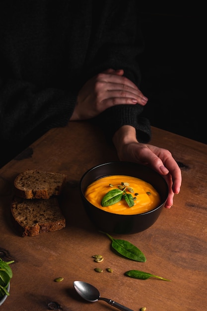 Donna che mangia una zuppa di zucca con pane integrale