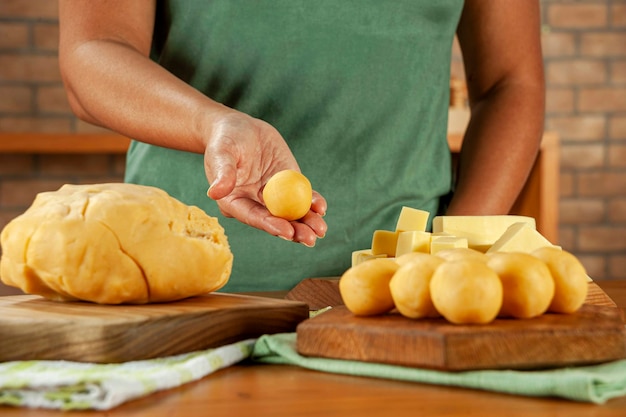 Donna che mantiene crocchetta ripiena di formaggio brasiliano bolinha de queijo su un tavolo di legno