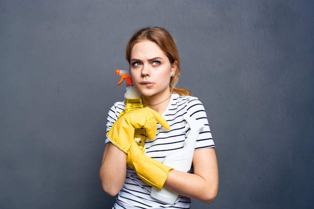 Donna che mantiene detersivo nelle mani di pulizia sfondo grigio stile di vita lavori domestici
