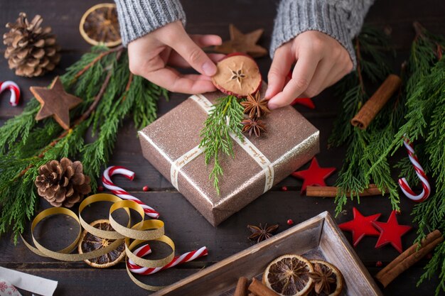 Donna che mantiene i regali di Natale posati su un tavolo di legno.