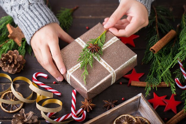 Donna che mantiene i regali di Natale posati su uno sfondo di tavolo in legno.