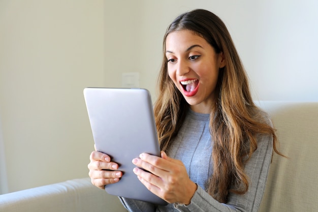 Donna che mantiene tablet pc sul divano di casa