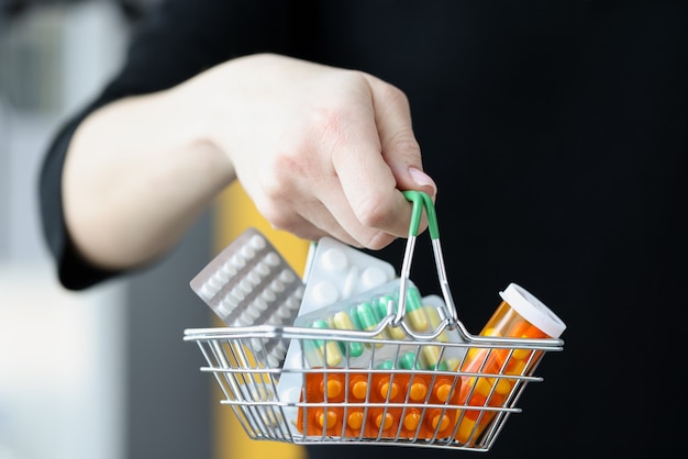 Donna che mantiene un cesto di medicinali in mano il primo piano. Concetto di polifarmacia