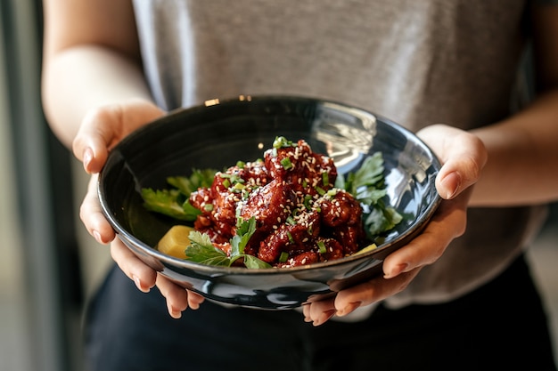 Donna che mantiene una ciotola di pollo marinato in salsa piccante con daikon