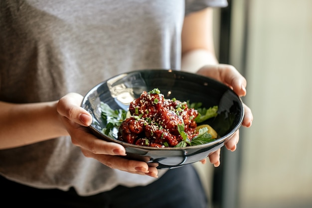 Donna che mantiene una ciotola di pollo marinato in salsa piccante con daikon