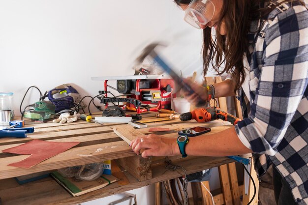 Donna che martella in un laboratorio di legno con sfocatura movimento