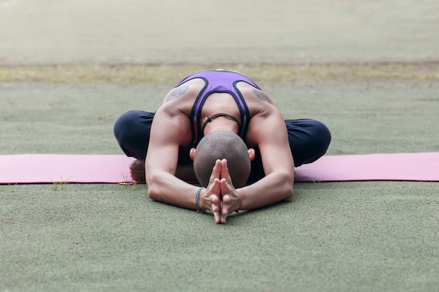 Donna che medita sul tappeto da yoga sul prato estivo verde